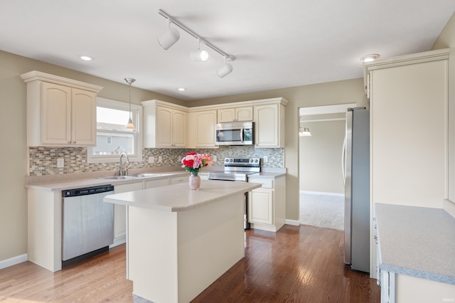 kitchen featuring hardwood / wood-style floors, stainless steel appliances, a kitchen island, pendant lighting, and sink