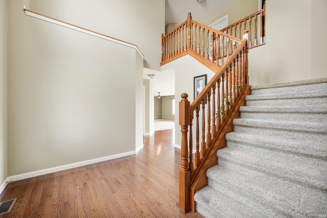 stairs featuring a high ceiling and wood-type flooring