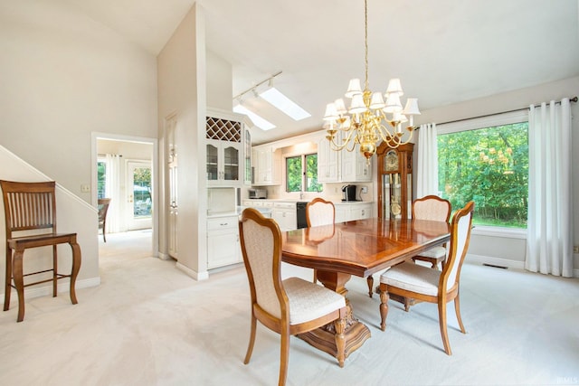 carpeted dining space featuring an inviting chandelier and lofted ceiling with skylight