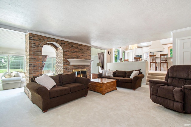 carpeted living room with ornamental molding, a brick fireplace, a notable chandelier, and a textured ceiling