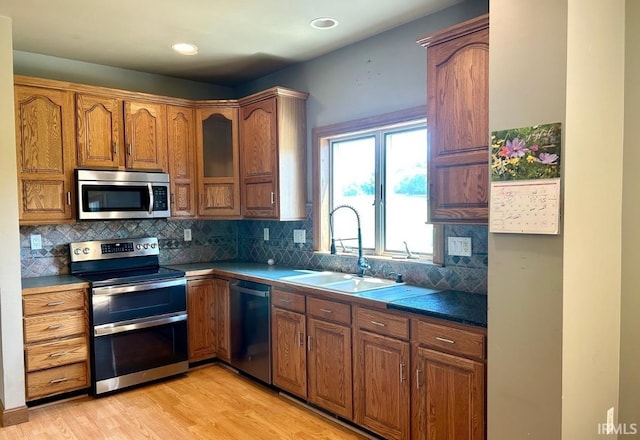 kitchen featuring sink, light hardwood / wood-style flooring, backsplash, and stainless steel appliances