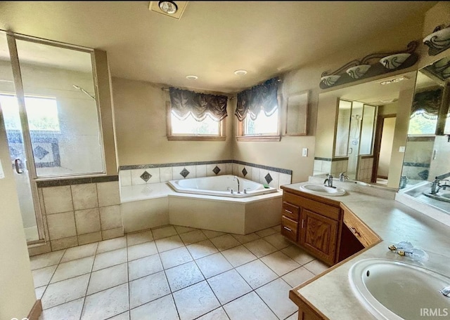 bathroom with tile patterned floors, vanity, tiled bath, and a wealth of natural light