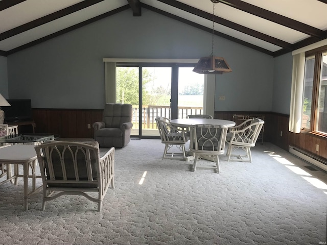 dining area with lofted ceiling with beams, a baseboard radiator, carpet, and wooden walls