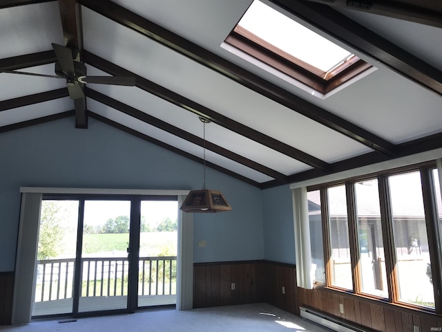 empty room with a healthy amount of sunlight, vaulted ceiling with skylight, and a baseboard heating unit