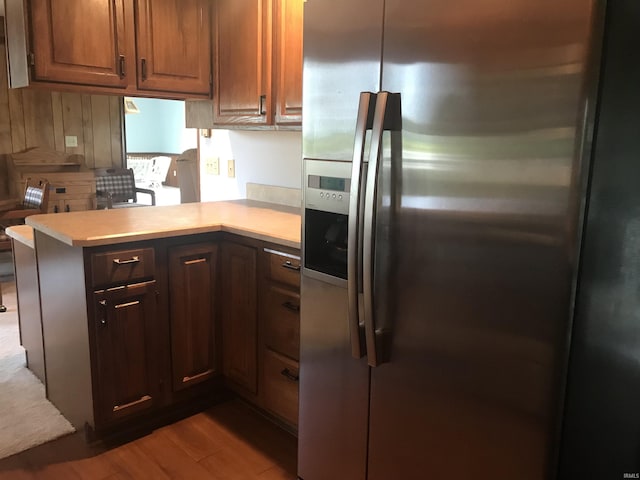 kitchen with stainless steel fridge with ice dispenser, light hardwood / wood-style floors, and kitchen peninsula