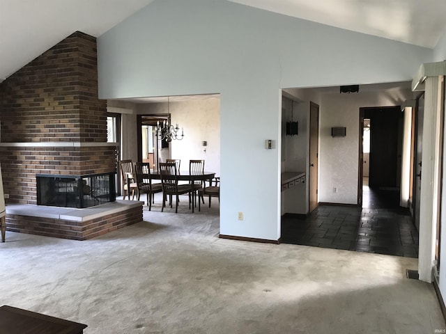 unfurnished living room with an inviting chandelier, high vaulted ceiling, dark carpet, and a brick fireplace