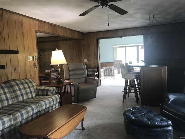 carpeted living room with wooden walls and ceiling fan