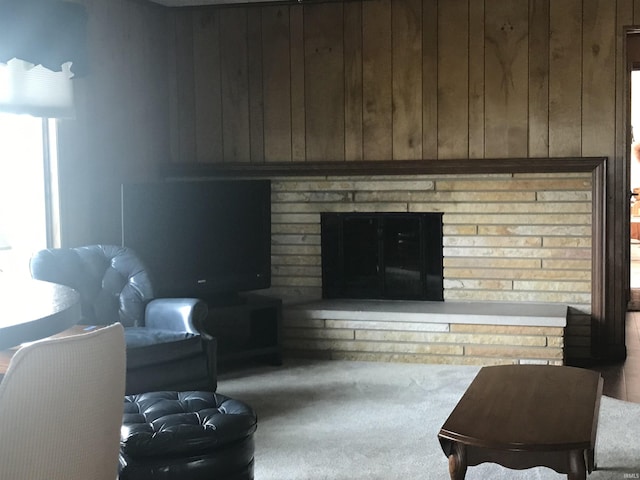 living room with a fireplace, wooden walls, and carpet