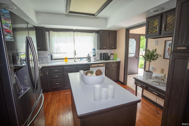 kitchen featuring white dishwasher, sink, black refrigerator, dark hardwood / wood-style floors, and a center island