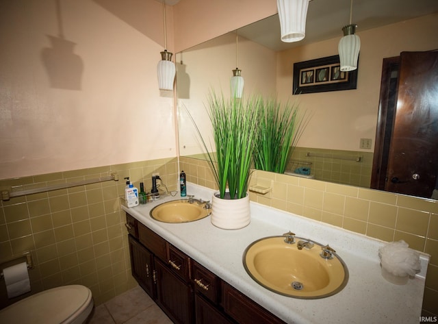 bathroom with tile patterned floors, tile walls, double vanity, decorative backsplash, and toilet