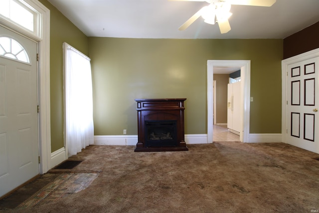 unfurnished living room with ceiling fan and carpet