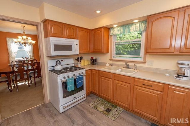 kitchen featuring white appliances, an inviting chandelier, carpet floors, hanging light fixtures, and sink