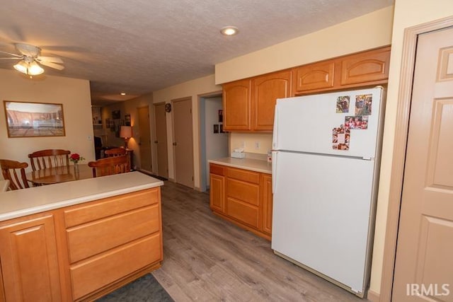 kitchen featuring a textured ceiling, white refrigerator, light wood-type flooring, and ceiling fan