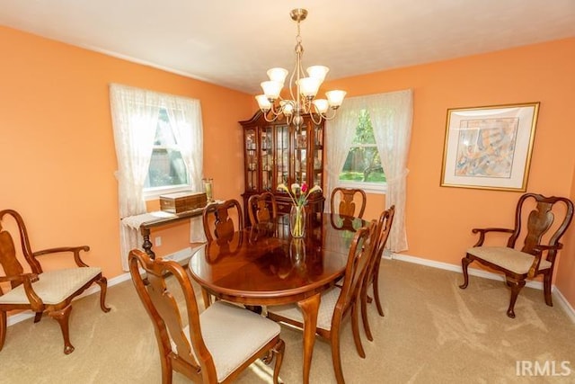 dining space featuring light carpet and an inviting chandelier