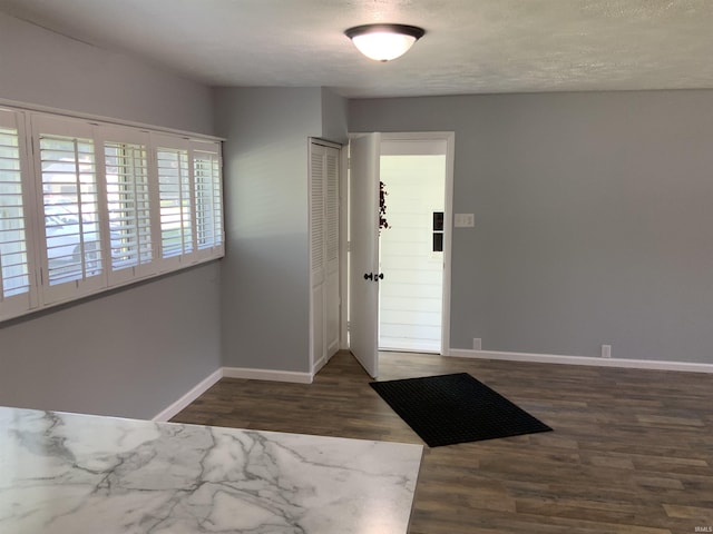 foyer entrance with a textured ceiling and dark hardwood / wood-style floors