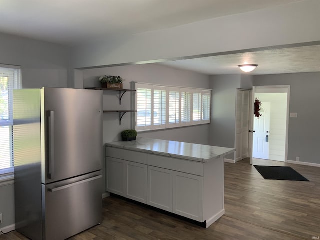 kitchen with dark wood-type flooring, stainless steel fridge, a wealth of natural light, and white cabinetry