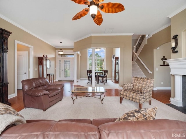 living room with wood-type flooring, ceiling fan, and crown molding