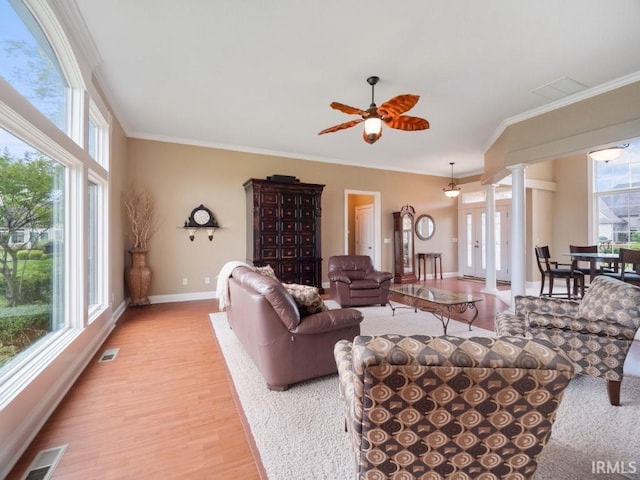 living room featuring plenty of natural light, crown molding, ornate columns, and light hardwood / wood-style floors