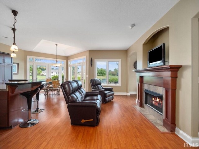 living room with a tile fireplace, hardwood / wood-style floors, and french doors