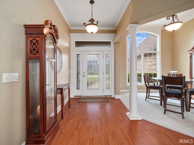 carpeted entryway with ornate columns and ornamental molding