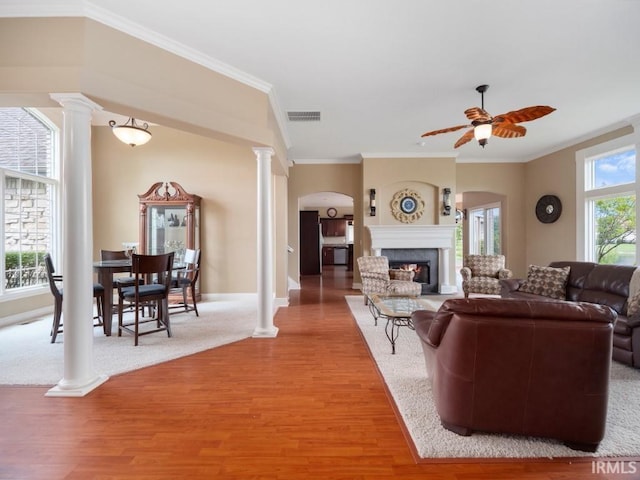 living room featuring ornate columns, crown molding, ceiling fan, and wood-type flooring