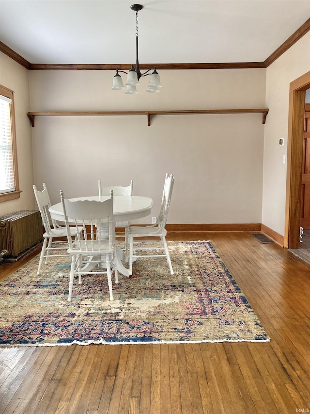 unfurnished dining area with hardwood / wood-style flooring, radiator heating unit, and an inviting chandelier