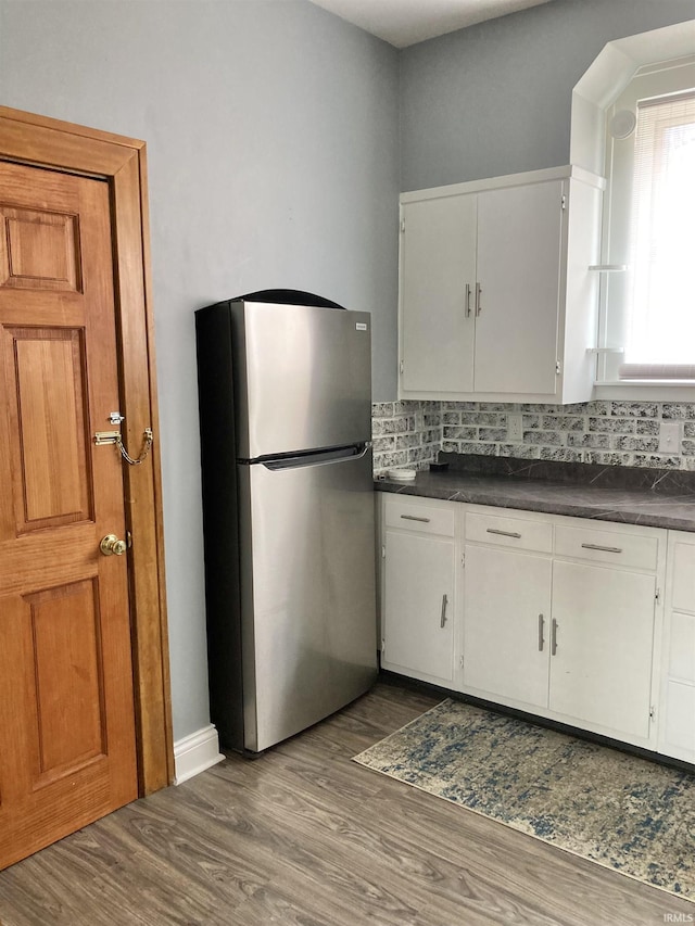 kitchen with white cabinets, tasteful backsplash, dark hardwood / wood-style floors, and stainless steel fridge