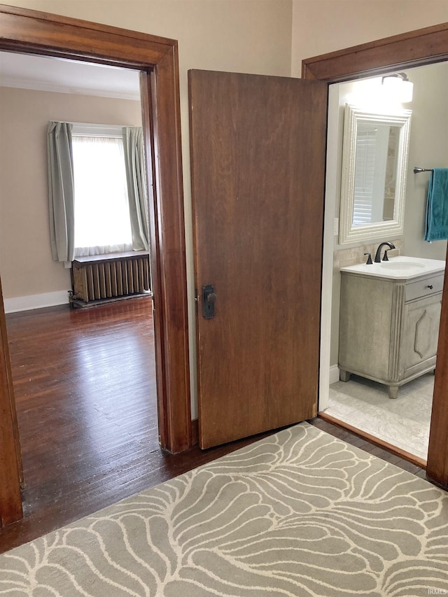 hall with dark wood-type flooring, radiator, and sink