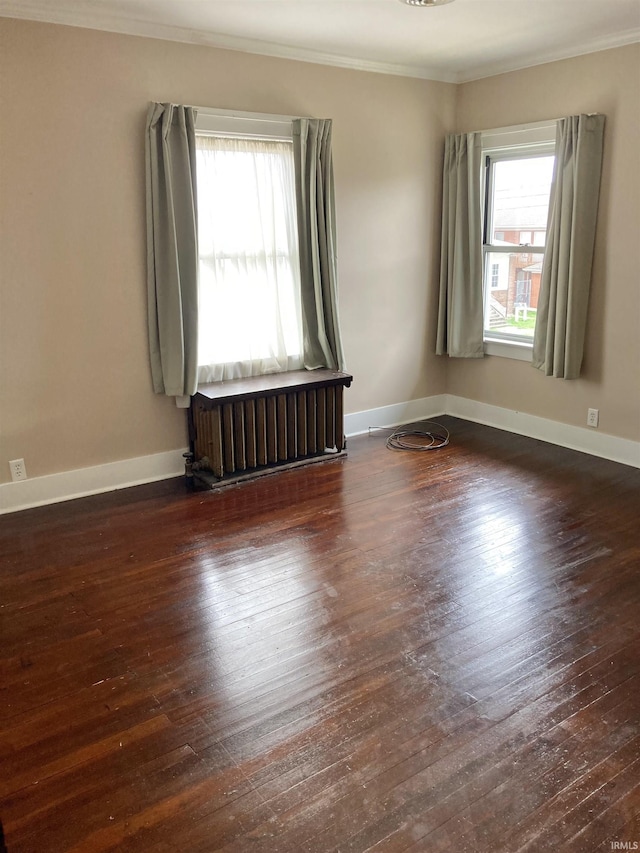 empty room featuring crown molding, plenty of natural light, dark hardwood / wood-style floors, and radiator