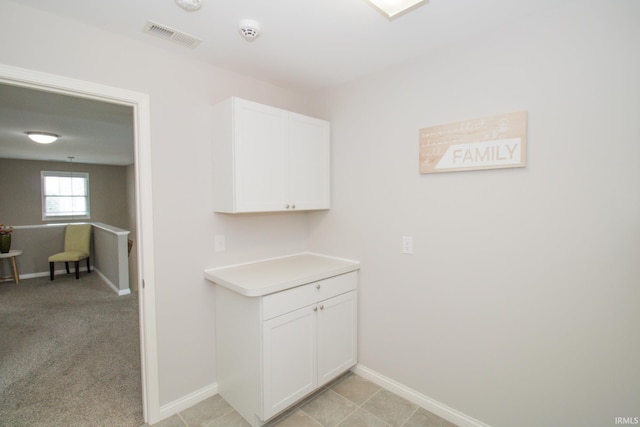 interior space with white cabinetry and light carpet