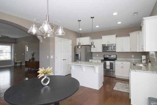 kitchen featuring appliances with stainless steel finishes, decorative light fixtures, white cabinetry, sink, and a center island