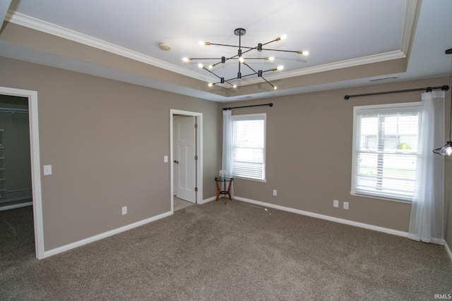 unfurnished bedroom featuring a notable chandelier, a walk in closet, a raised ceiling, and carpet