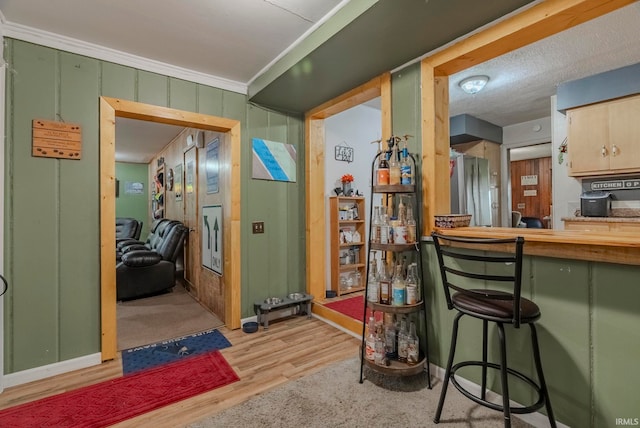 interior space with crown molding, a textured ceiling, light hardwood / wood-style floors, and wood walls