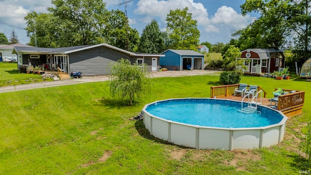 view of swimming pool featuring a garage, a yard, a deck, and a storage shed