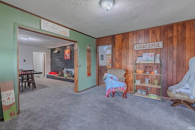 sitting room featuring crown molding, wooden walls, a textured ceiling, and carpet