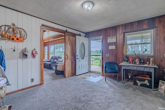 entryway with light carpet, a textured ceiling, and wood walls