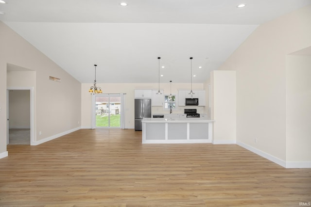 unfurnished living room with light hardwood / wood-style floors, a chandelier, and high vaulted ceiling