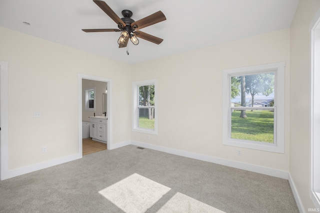 unfurnished bedroom featuring ensuite bath, ceiling fan, and light colored carpet