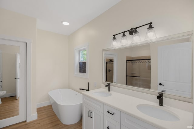 bathroom with hardwood / wood-style floors, toilet, dual bowl vanity, and a tub