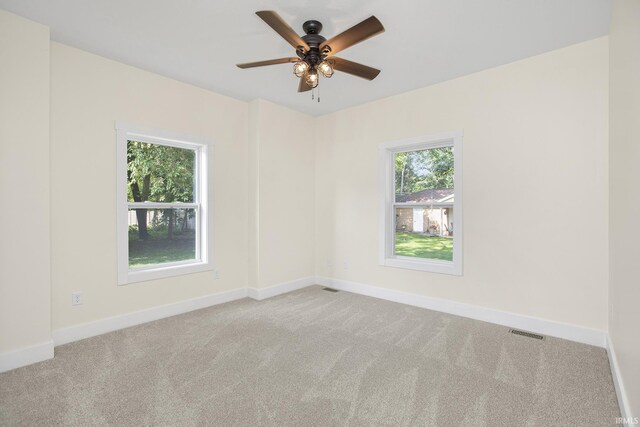 carpeted spare room featuring plenty of natural light and ceiling fan