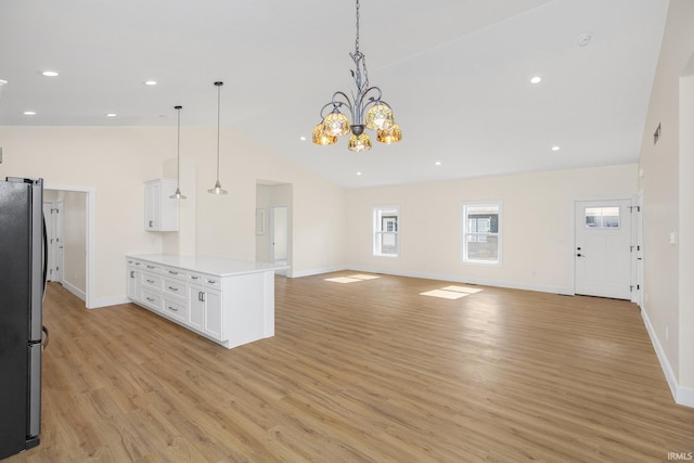 kitchen with hanging light fixtures, white cabinets, stainless steel fridge, light hardwood / wood-style floors, and lofted ceiling