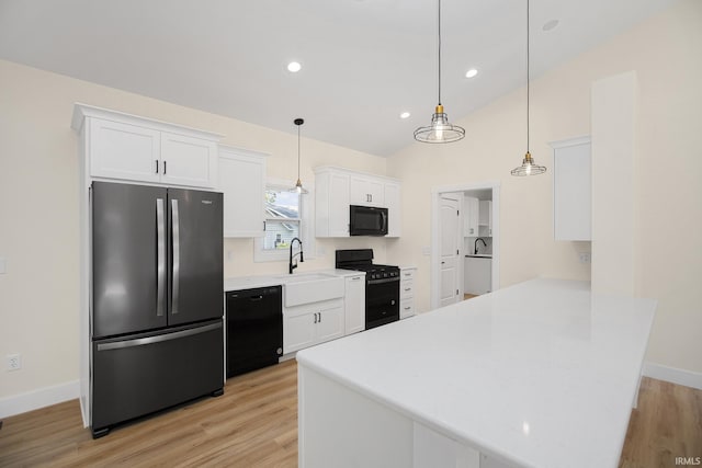 kitchen with white cabinets, light hardwood / wood-style floors, black appliances, and kitchen peninsula