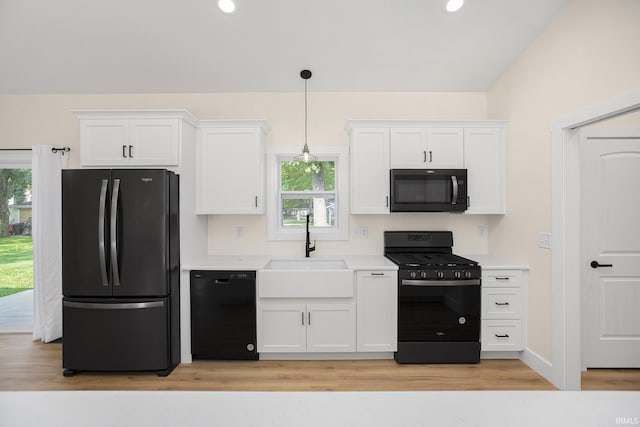 kitchen with light hardwood / wood-style floors, white cabinetry, and black appliances