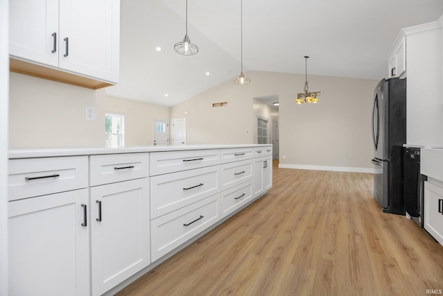 kitchen with white cabinetry, pendant lighting, stainless steel fridge, light hardwood / wood-style flooring, and lofted ceiling