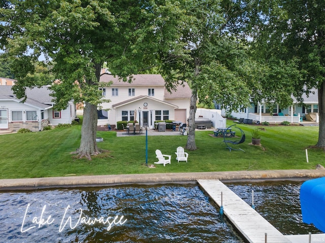 back of house with a water view, a patio area, and a yard