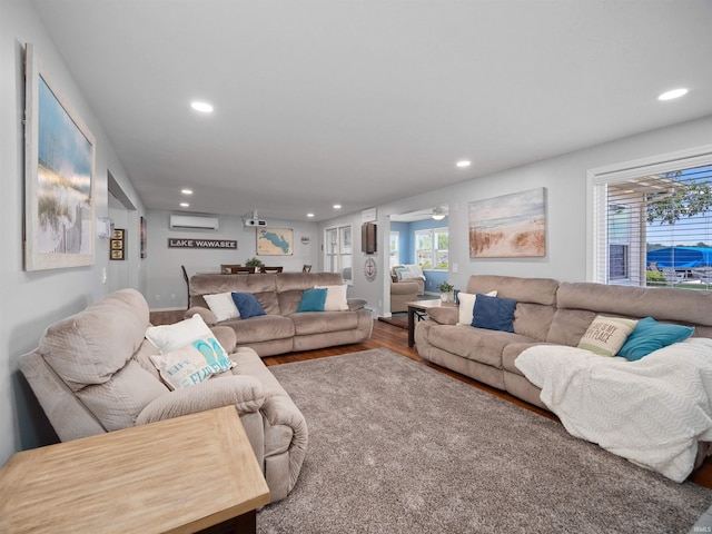 living room with ceiling fan, a wall mounted AC, and wood-type flooring