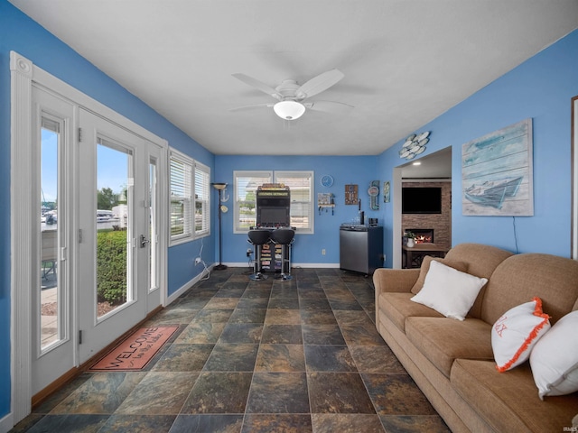 living room with ceiling fan and a stone fireplace