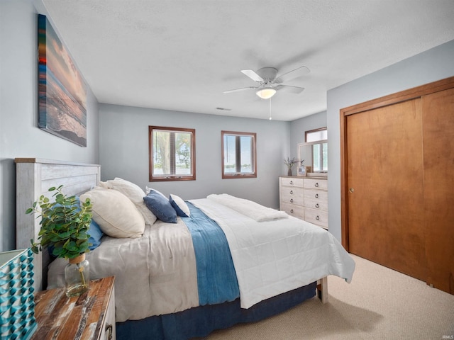 bedroom with ceiling fan, carpet, a closet, and a textured ceiling