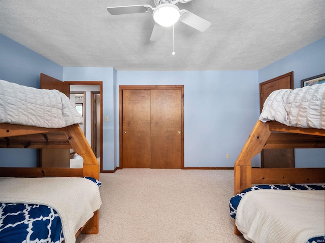 bedroom with a textured ceiling, ceiling fan, a closet, and light colored carpet