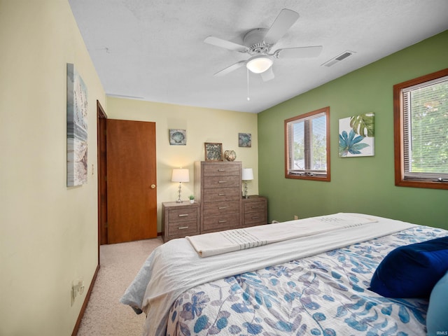 carpeted bedroom featuring ceiling fan, multiple windows, and a textured ceiling